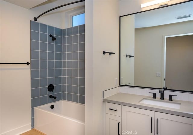 bathroom featuring tiled shower / bath combo and vanity