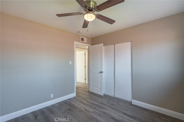 unfurnished bedroom with dark wood-type flooring, ceiling fan, and a closet