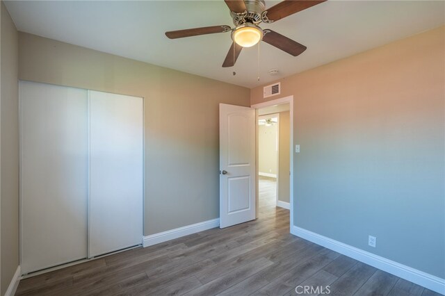 unfurnished bedroom featuring ceiling fan, a closet, and hardwood / wood-style floors