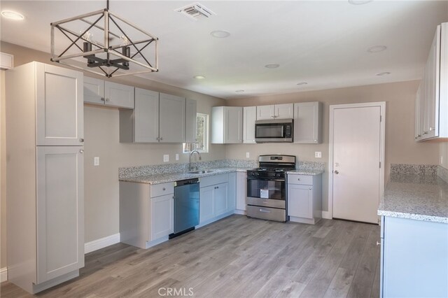 kitchen with sink, pendant lighting, appliances with stainless steel finishes, and white cabinets