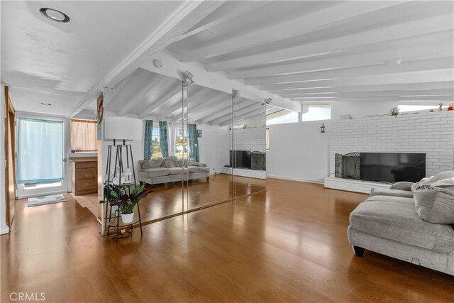 living room with a fireplace, hardwood / wood-style flooring, and vaulted ceiling with beams