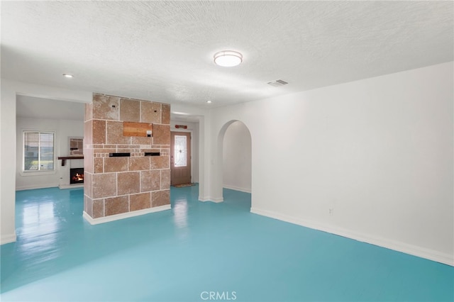 unfurnished living room with a large fireplace, a textured ceiling, and concrete flooring