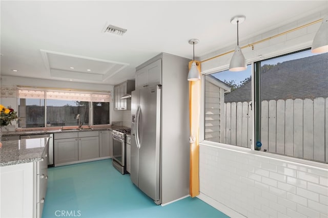 kitchen featuring appliances with stainless steel finishes, sink, stone countertops, hanging light fixtures, and gray cabinets