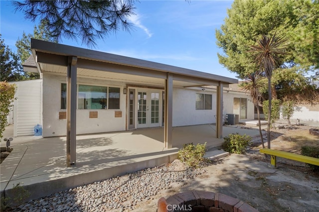 rear view of property with central AC unit, french doors, a patio area, and a fire pit