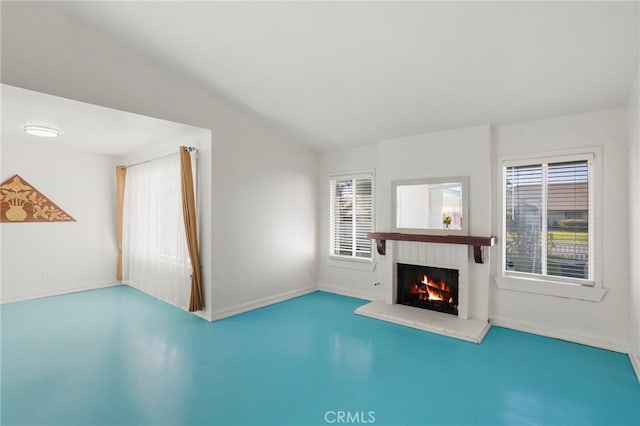 unfurnished living room featuring vaulted ceiling, a brick fireplace, and plenty of natural light