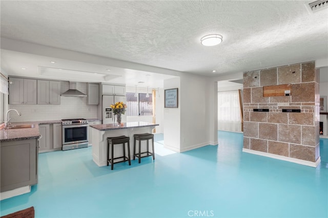 kitchen featuring a center island, sink, appliances with stainless steel finishes, gray cabinetry, and wall chimney exhaust hood