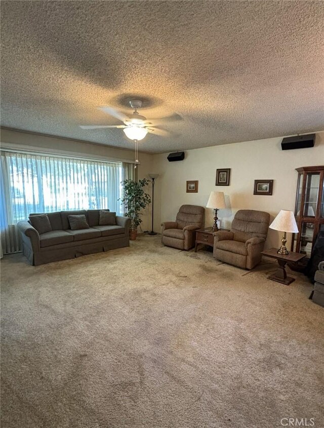 living room with carpet, ceiling fan, and a textured ceiling