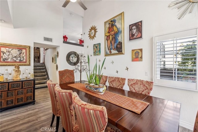 dining space with breakfast area, a towering ceiling, wood-type flooring, and ceiling fan