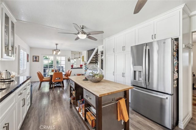 kitchen with dark wood-type flooring, wood counters, white cabinetry, stainless steel fridge, and ceiling fan