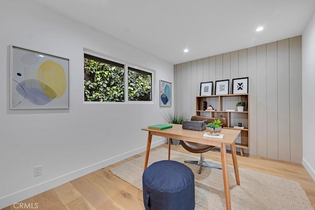 home office featuring light hardwood / wood-style flooring and wood walls