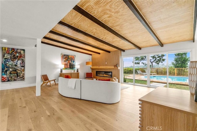 unfurnished living room with a large fireplace, lofted ceiling with beams, wood ceiling, and light wood-type flooring