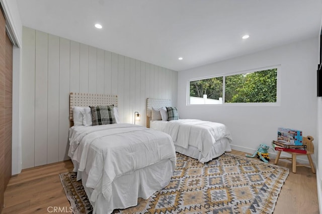 bedroom with a closet, wooden walls, and hardwood / wood-style flooring