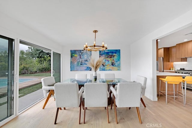 dining space featuring light wood-type flooring and a notable chandelier