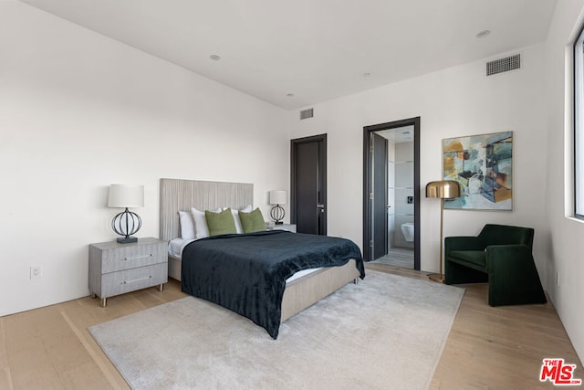 bedroom featuring ensuite bath and light wood-type flooring