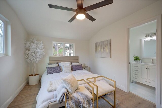 bedroom featuring ensuite bathroom, sink, vaulted ceiling, light wood-type flooring, and ceiling fan