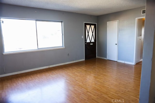 unfurnished room featuring plenty of natural light, a textured ceiling, and hardwood / wood-style floors