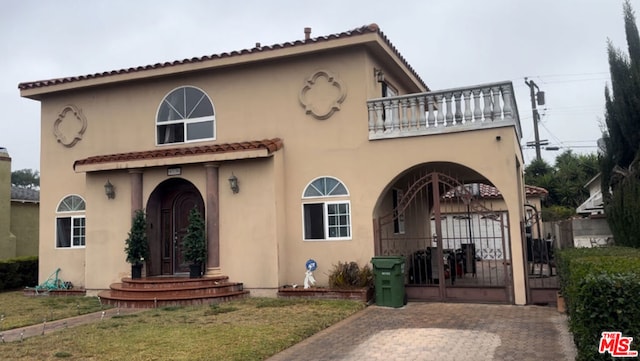 back of property featuring a balcony and a lawn