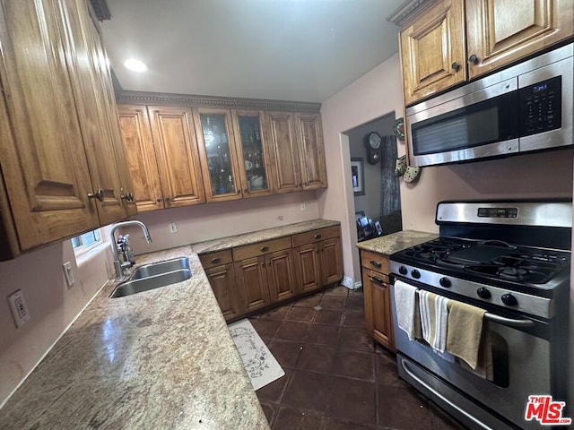 kitchen featuring dark tile patterned floors, light stone countertops, sink, and stainless steel appliances