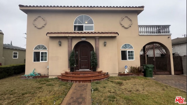 mediterranean / spanish-style home featuring a balcony and a front yard