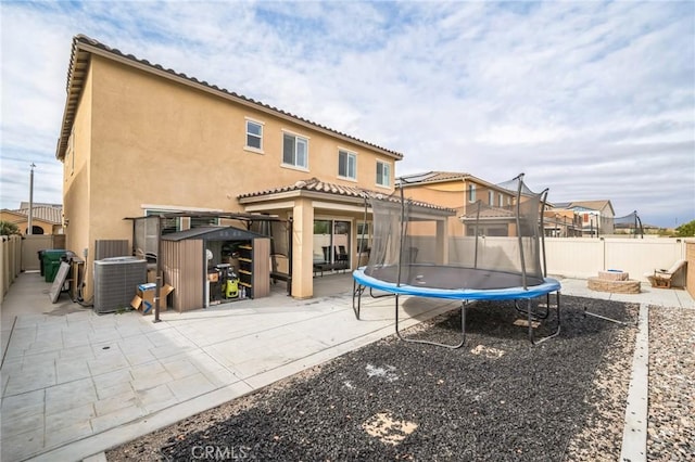 rear view of property featuring central AC, a trampoline, a patio area, and a fire pit