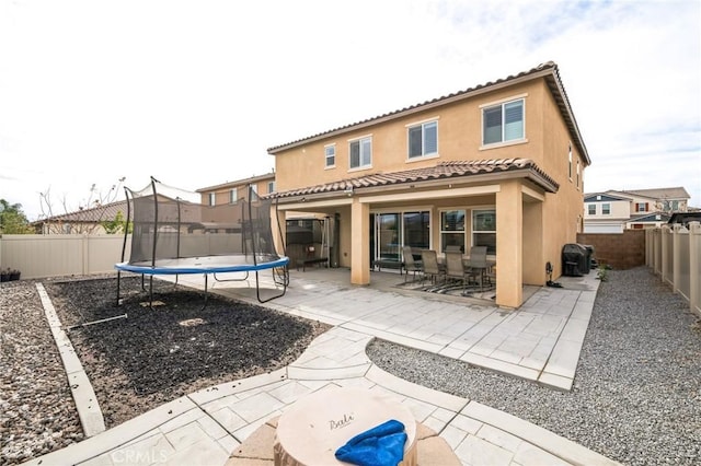 back of property with a trampoline and a patio