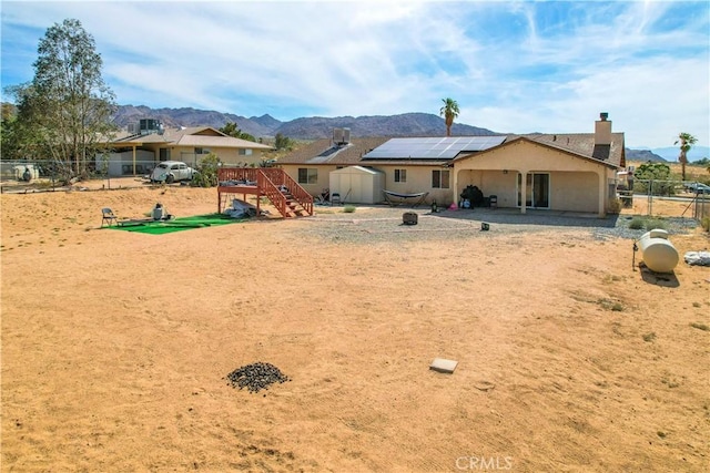 rear view of house featuring a mountain view, a storage shed, and solar panels