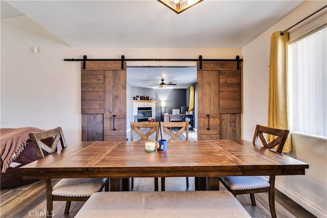 dining area with ceiling fan, a barn door, and hardwood / wood-style floors