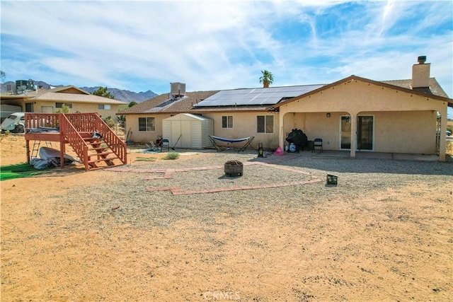 back of property with a fire pit, central AC unit, a wooden deck, a shed, and a patio