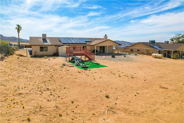 back of property with a mountain view and solar panels