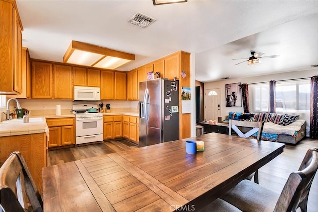 kitchen with white appliances, dark hardwood / wood-style flooring, sink, tile countertops, and ceiling fan