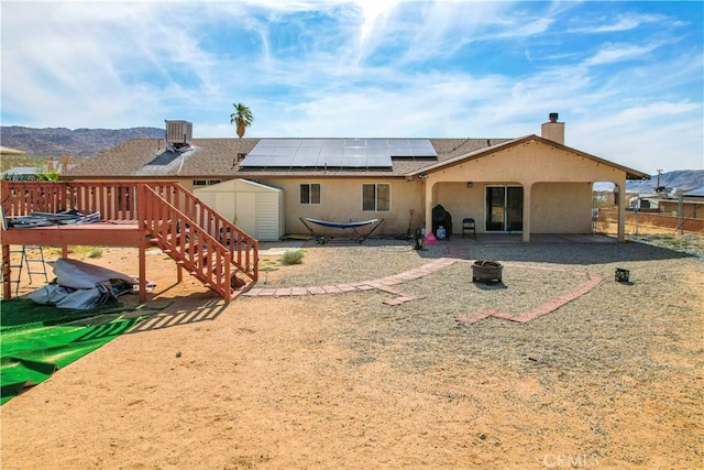 rear view of property with a storage shed, central air condition unit, a patio area, and a deck with mountain view