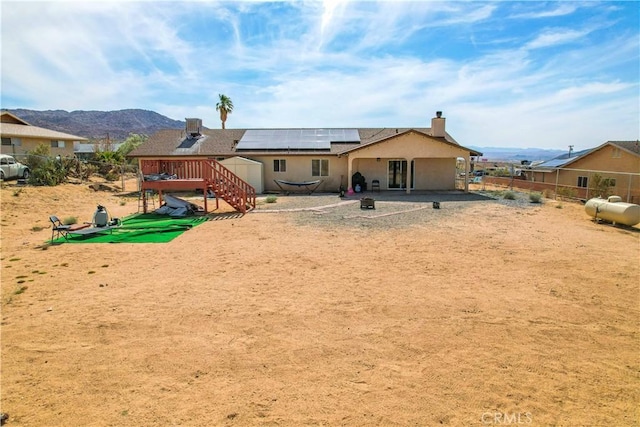 rear view of house featuring a patio area, a mountain view, and solar panels