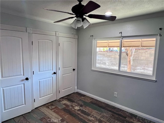 unfurnished bedroom featuring a textured ceiling, ceiling fan, ornamental molding, and dark hardwood / wood-style flooring