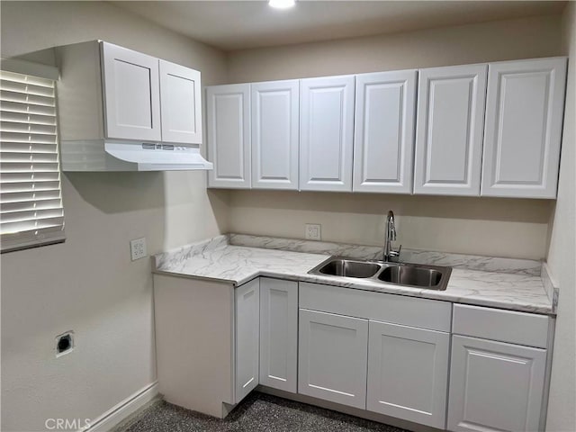 kitchen featuring light stone countertops, sink, and white cabinetry