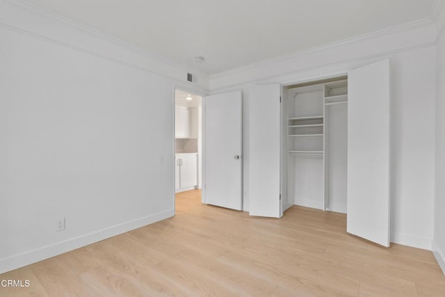 unfurnished bedroom with light wood-type flooring, a closet, and crown molding