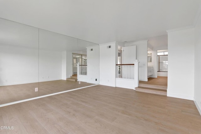 unfurnished living room featuring ornamental molding and light hardwood / wood-style floors