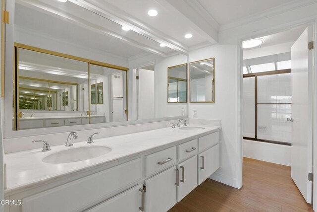 bathroom featuring hardwood / wood-style flooring, shower / bath combination with glass door, vanity, and ornamental molding