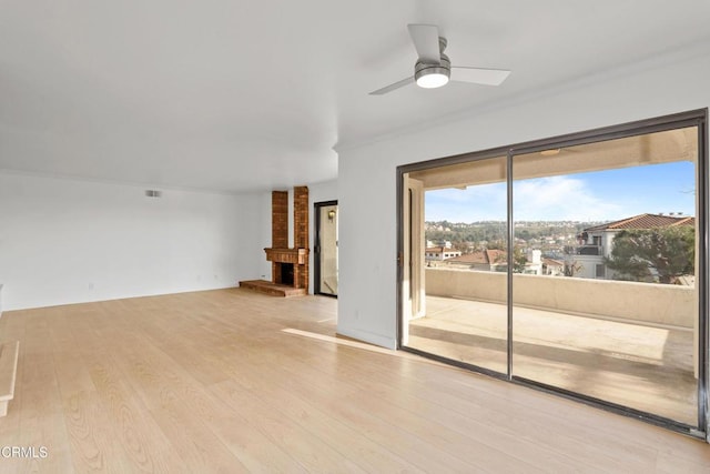 unfurnished living room featuring a brick fireplace, light hardwood / wood-style flooring, and ceiling fan