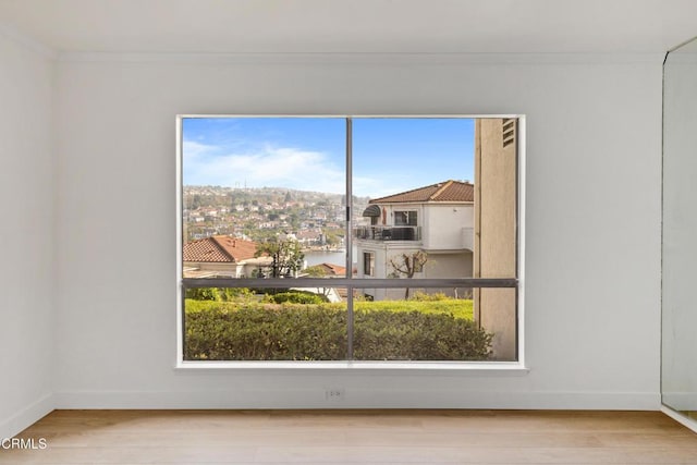 unfurnished room with light wood-type flooring, a wealth of natural light, and ornamental molding