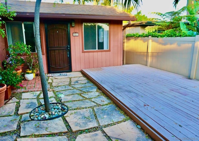 view of exterior entry with a patio area and a wooden deck