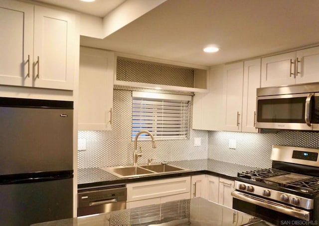 kitchen featuring decorative backsplash, appliances with stainless steel finishes, and white cabinetry