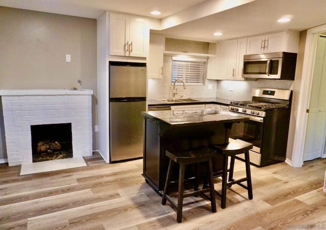 kitchen featuring a center island, white cabinets, sink, appliances with stainless steel finishes, and a kitchen bar