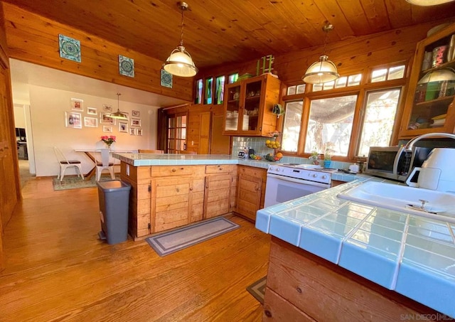 kitchen with kitchen peninsula, sink, pendant lighting, tile countertops, and white range with electric cooktop