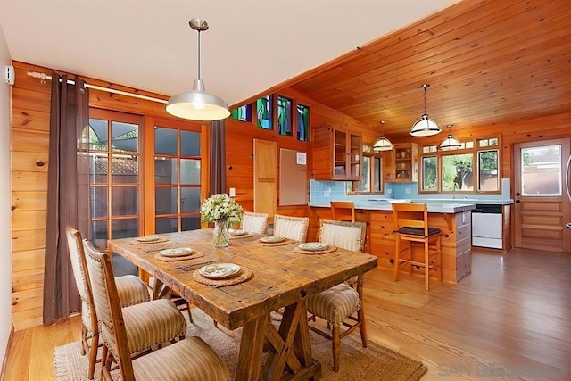 dining room featuring wood walls, wooden ceiling, and light hardwood / wood-style floors