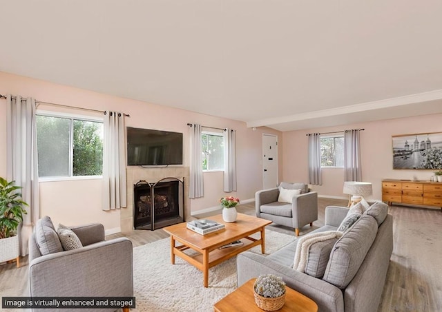 living room with plenty of natural light, light hardwood / wood-style floors, and a tiled fireplace