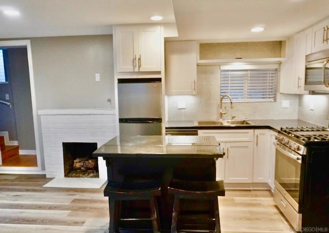 kitchen featuring white cabinets, a kitchen bar, stainless steel appliances, and tasteful backsplash