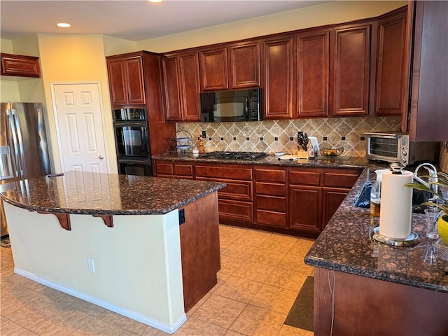 kitchen with a center island, decorative backsplash, dark stone counters, and black appliances