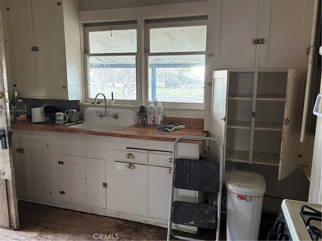 kitchen with sink, white cabinetry, range with gas cooktop, and butcher block counters