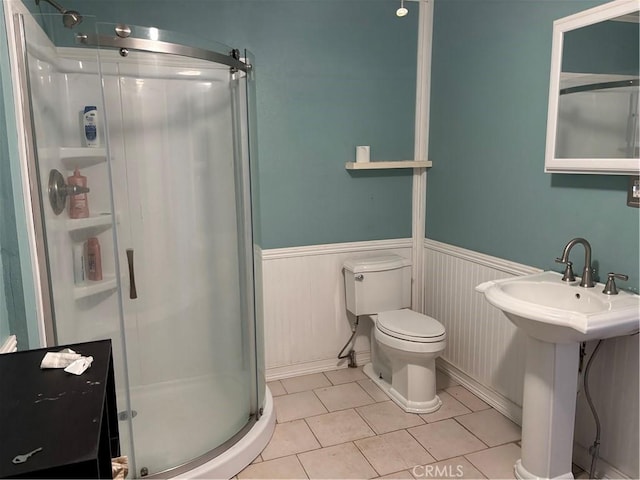 bathroom with an enclosed shower, sink, tile patterned flooring, and toilet