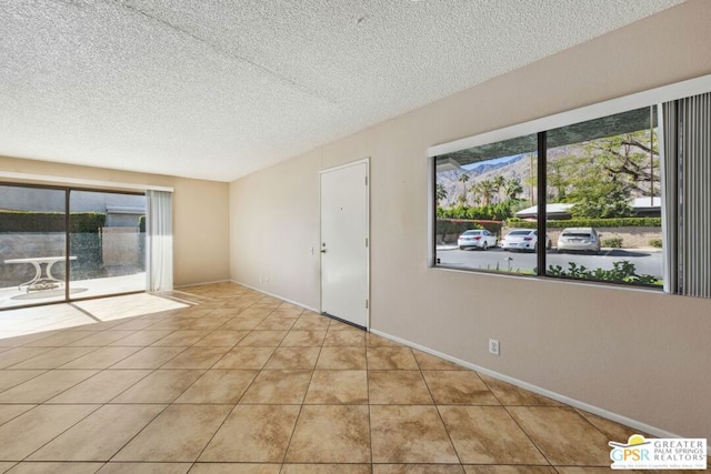 unfurnished room featuring light tile patterned floors, a mountain view, and a textured ceiling